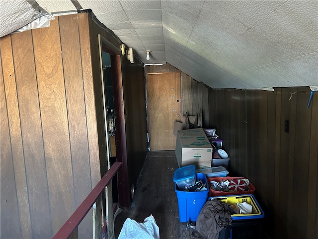 bonus room with lofted ceiling and wooden walls