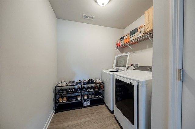 clothes washing area featuring light hardwood / wood-style floors and separate washer and dryer