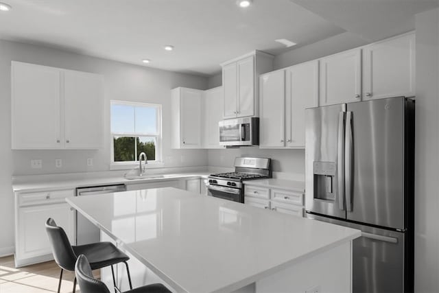 kitchen featuring white cabinets, a center island, stainless steel appliances, sink, and a breakfast bar area