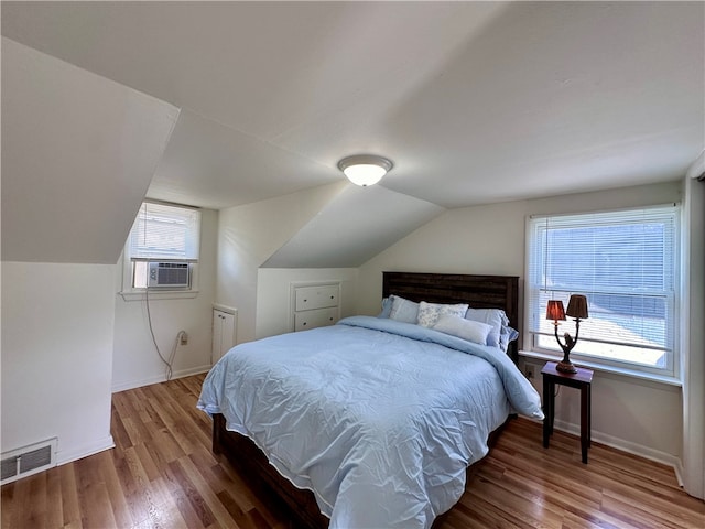 bedroom featuring lofted ceiling, multiple windows, wood-type flooring, and cooling unit