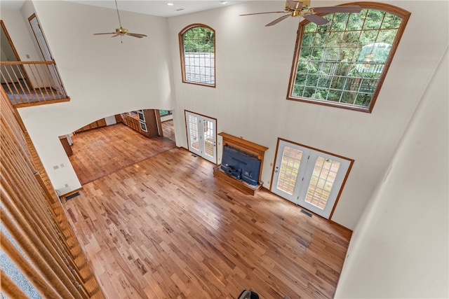 living room featuring wood-type flooring, a high ceiling, and ceiling fan