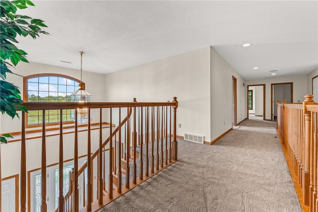 hallway with an inviting chandelier and light carpet