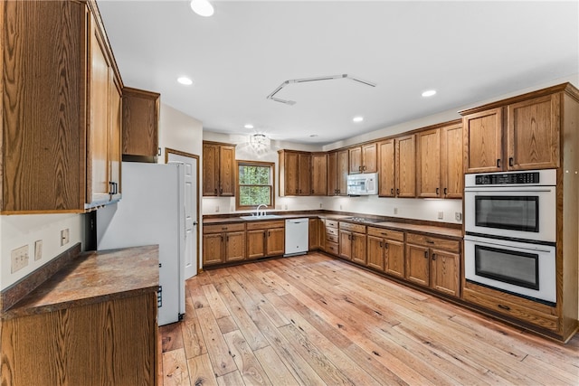 kitchen featuring white appliances, sink, and light hardwood / wood-style floors