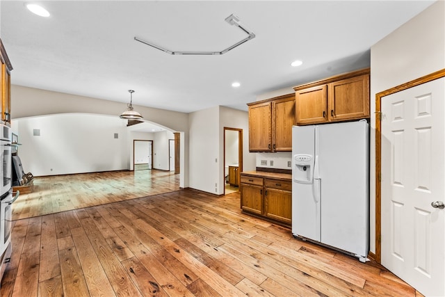 kitchen with decorative light fixtures, light hardwood / wood-style floors, and white fridge with ice dispenser