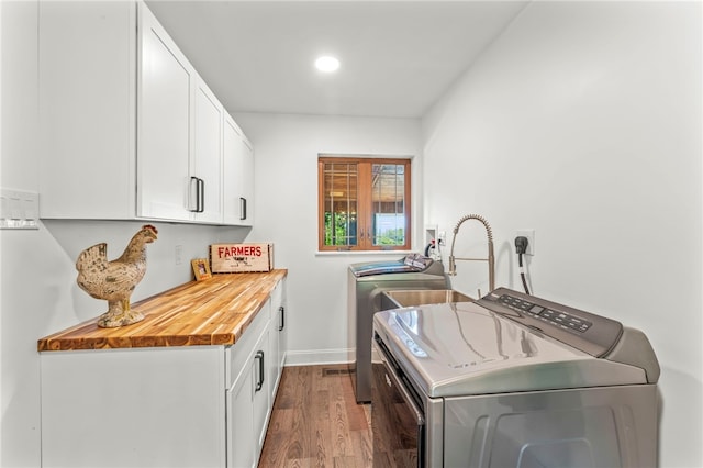 clothes washing area featuring cabinets, washer and dryer, and dark hardwood / wood-style floors