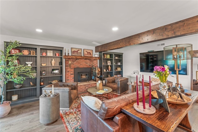 living room featuring a brick fireplace, hardwood / wood-style floors, and a notable chandelier