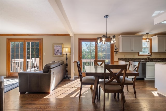 dining space featuring beamed ceiling, wood-type flooring, a notable chandelier, and sink