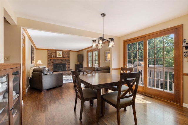 dining area with a fireplace, crown molding, a notable chandelier, and dark hardwood / wood-style floors