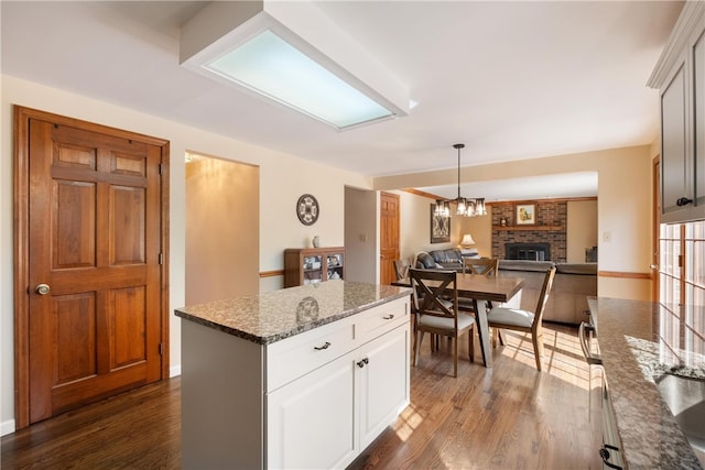 kitchen featuring white cabinets, a kitchen island, a fireplace, and dark hardwood / wood-style flooring