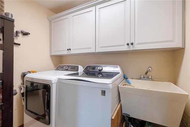 laundry area featuring washing machine and clothes dryer, cabinets, and sink