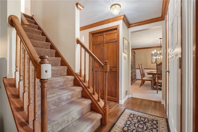 interior space featuring hardwood / wood-style floors, crown molding, a notable chandelier, and a textured ceiling