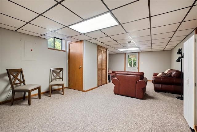 living room featuring a paneled ceiling, light colored carpet, and electric panel