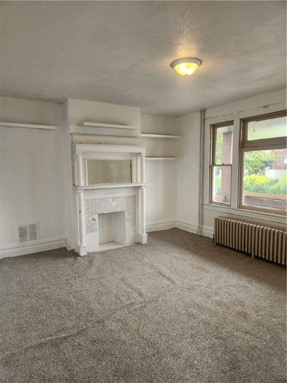 unfurnished living room with a fireplace, radiator, carpet flooring, and a textured ceiling