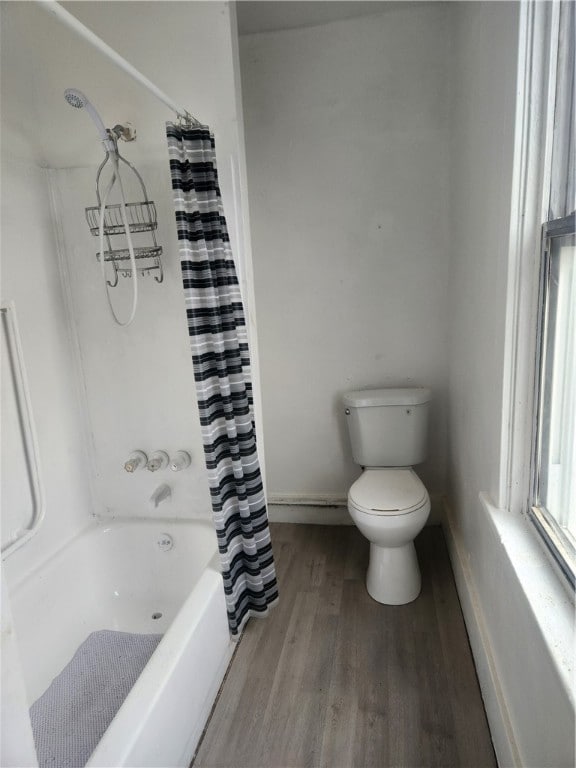 bathroom with hardwood / wood-style floors, toilet, and shower / bathtub combination with curtain