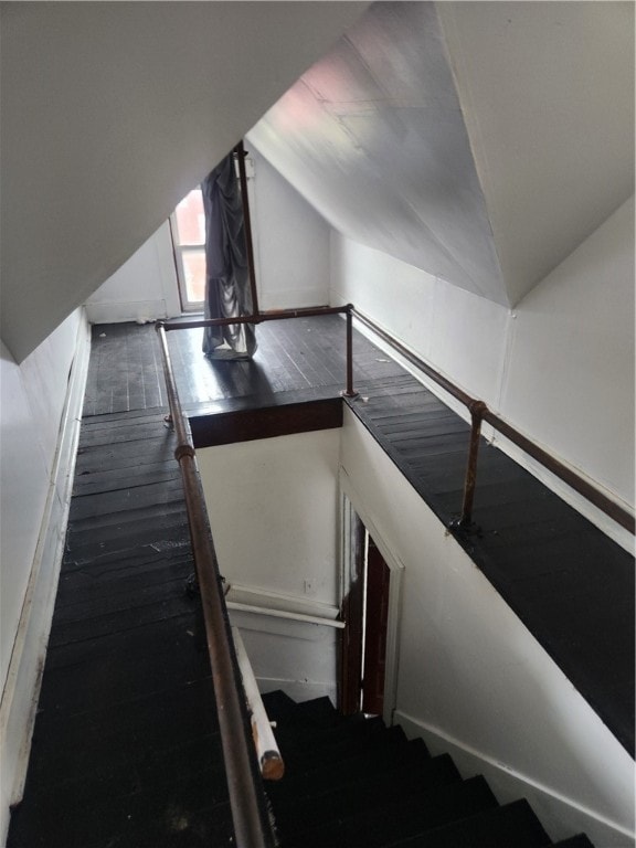 stairs with wood-type flooring and vaulted ceiling