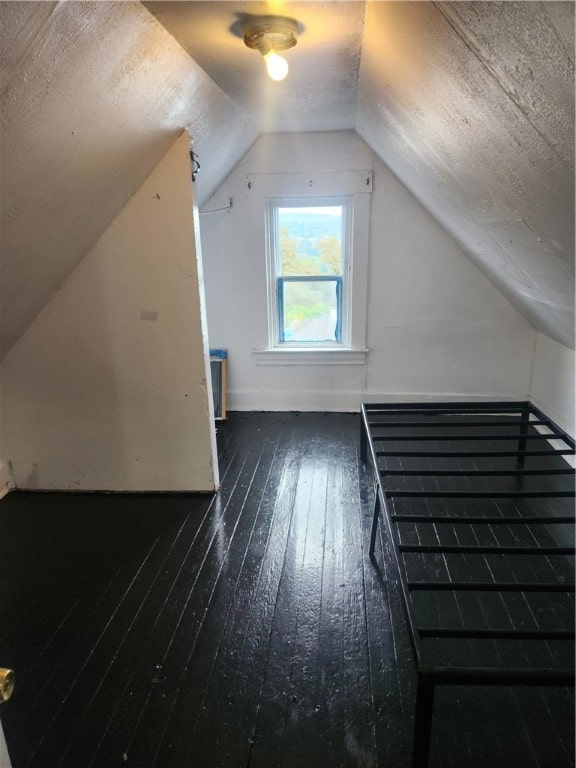 bonus room with dark wood-type flooring and vaulted ceiling