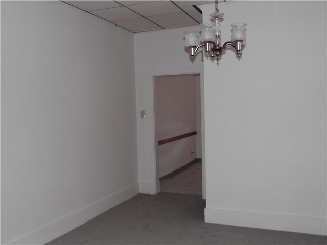 spare room featuring a chandelier, a paneled ceiling, and carpet flooring