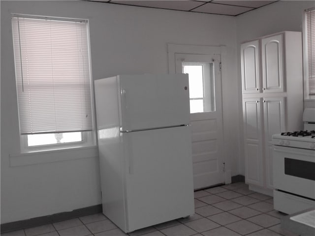 kitchen featuring plenty of natural light, white appliances, white cabinets, and light tile patterned flooring