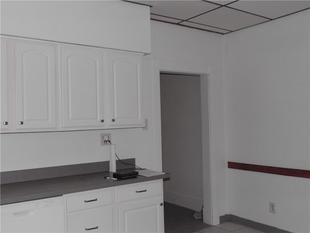 kitchen featuring dishwasher, light tile patterned floors, a paneled ceiling, and white cabinets