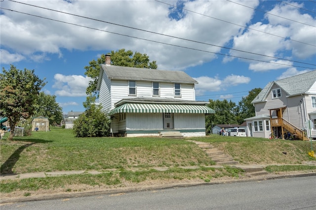 view of front facade featuring a shed and a front lawn