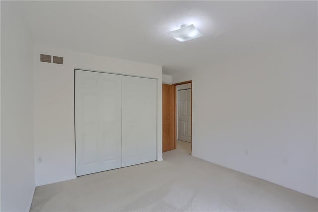 unfurnished bedroom with a closet and light carpet