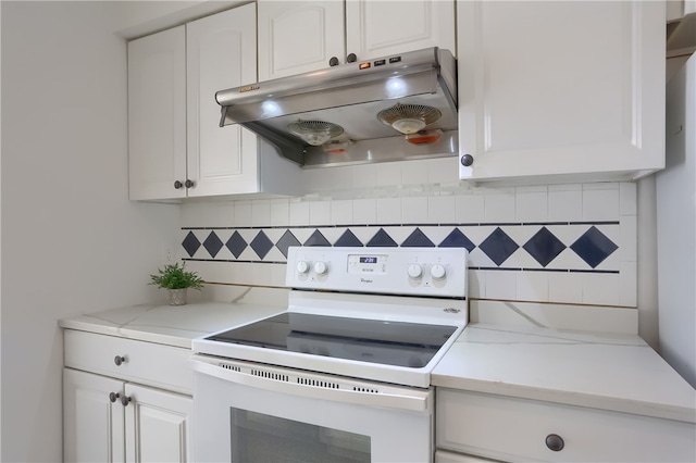 kitchen with light stone countertops, white cabinets, backsplash, and electric range