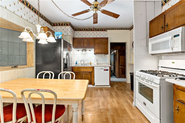 kitchen featuring light hardwood / wood-style flooring, white appliances, wood walls, ceiling fan, and pendant lighting