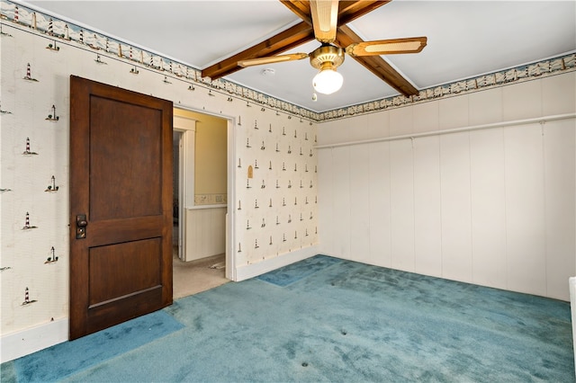 unfurnished room with ceiling fan, beamed ceiling, and carpet floors