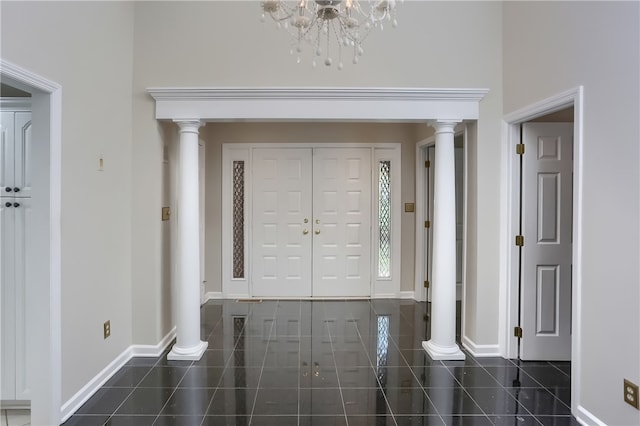 foyer entrance with dark tile patterned floors, a chandelier, and ornate columns