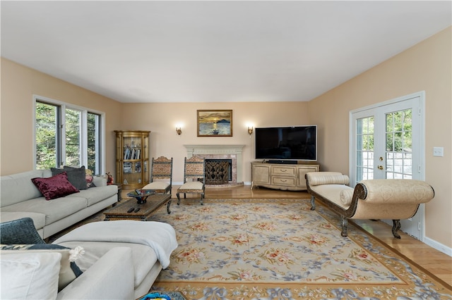 living room featuring french doors, wood-type flooring, and a brick fireplace