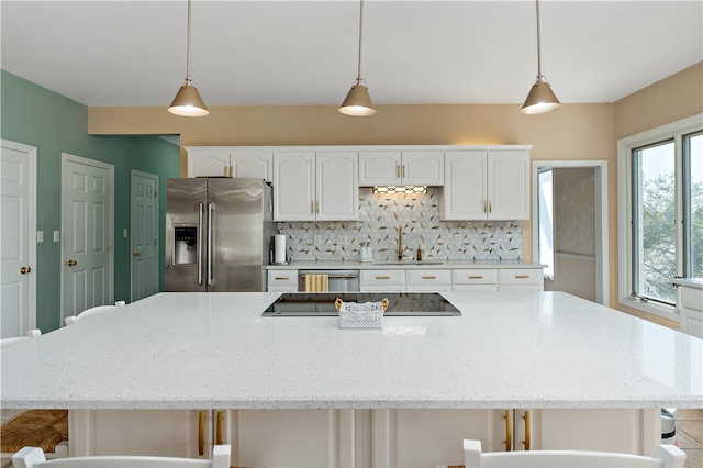 kitchen featuring stainless steel appliances, decorative light fixtures, decorative backsplash, and white cabinets