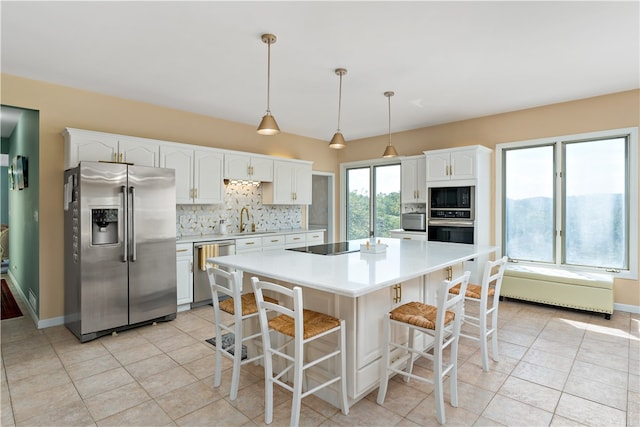 kitchen featuring black appliances, hanging light fixtures, white cabinetry, and a kitchen island