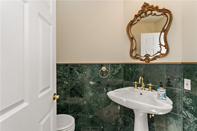 bathroom with tile walls, toilet, sink, and tasteful backsplash