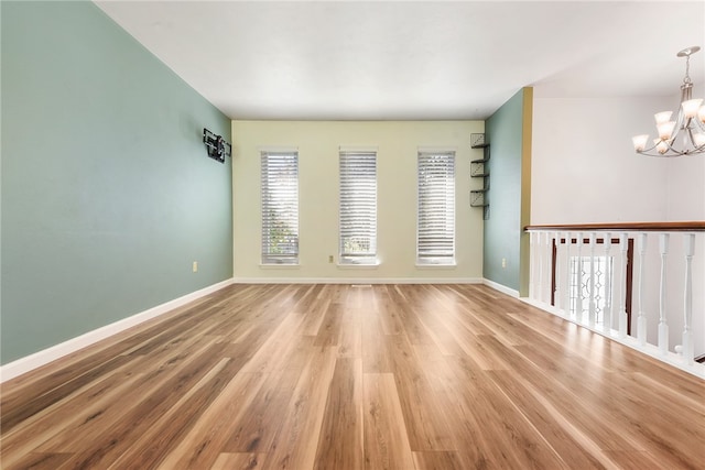 empty room with light wood-type flooring, plenty of natural light, and a notable chandelier