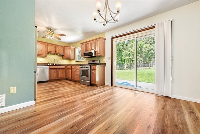 kitchen featuring ceiling fan with notable chandelier, stainless steel appliances, sink, decorative light fixtures, and light hardwood / wood-style flooring