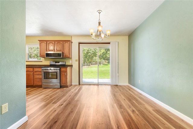 kitchen featuring decorative light fixtures, stainless steel appliances, plenty of natural light, and light hardwood / wood-style floors