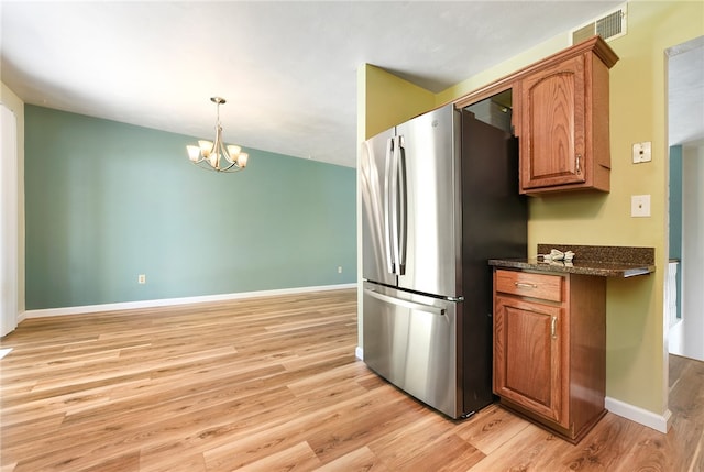 kitchen with stainless steel fridge, light hardwood / wood-style floors, and an inviting chandelier