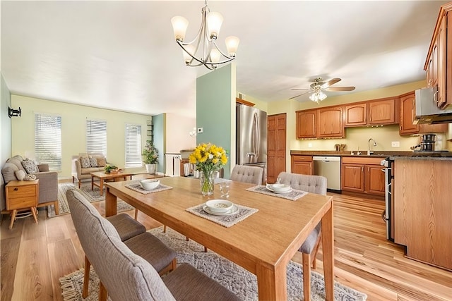 dining room featuring light hardwood / wood-style flooring, ceiling fan with notable chandelier, and sink