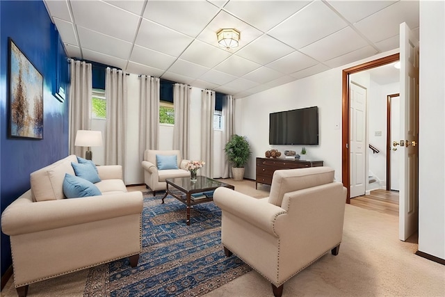 carpeted living room featuring a drop ceiling