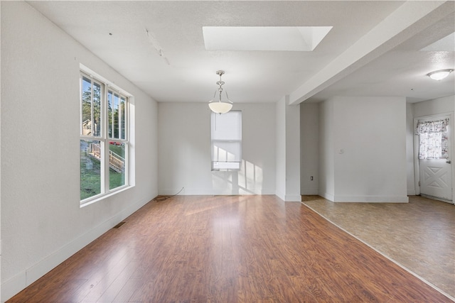 spare room with a skylight and wood-type flooring