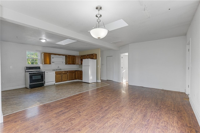 unfurnished living room with sink, beam ceiling, dark hardwood / wood-style flooring, and a skylight