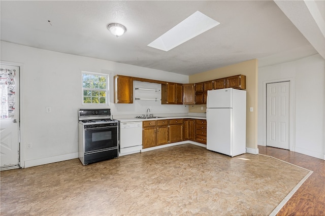 kitchen featuring a skylight, white appliances, a textured ceiling, and sink