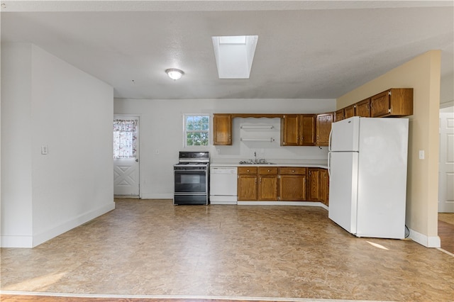 kitchen with a textured ceiling, sink, white appliances, and a skylight