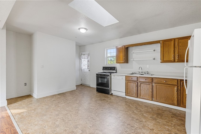 kitchen featuring a textured ceiling, sink, white appliances, and a skylight