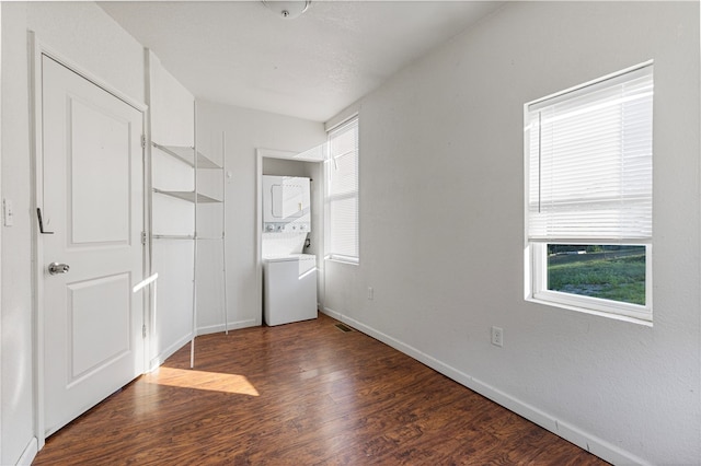 unfurnished bedroom featuring dark wood-type flooring and stacked washer / dryer