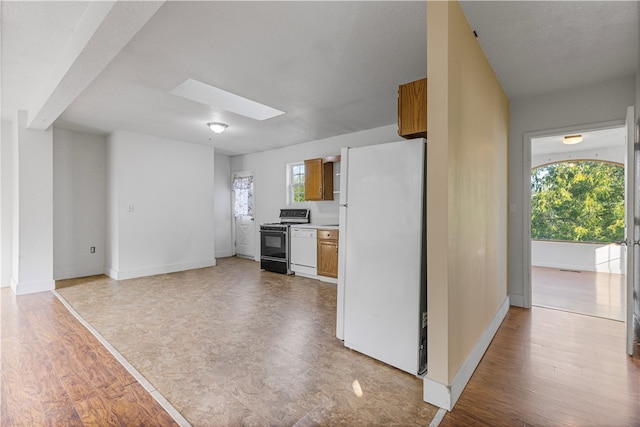 kitchen with a skylight, white appliances, and light hardwood / wood-style flooring