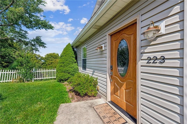 doorway to property featuring a lawn and fence