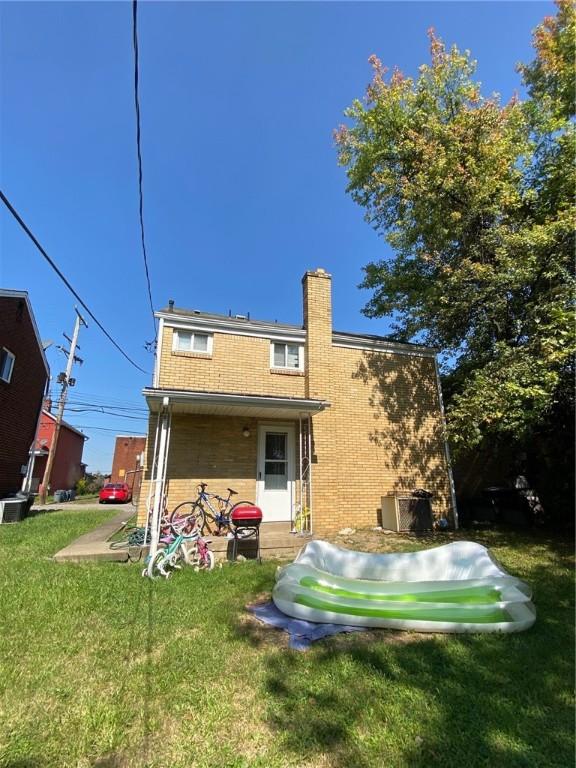 2608 Highland Ave, Mckeesport, PA 15132 - back of house featuring a lawn, a chimney, and brick siding