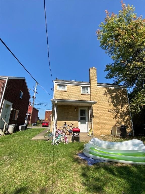 2608 Highland Ave, Mckeesport, PA 15132 - back of house featuring a lawn, a chimney, and brick siding