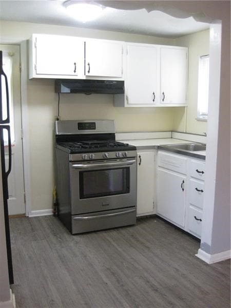 2608 Highland Ave, Mckeesport, PA 15132 - kitchen featuring gas range, under cabinet range hood, dark wood-style flooring, a sink, and white cabinetry